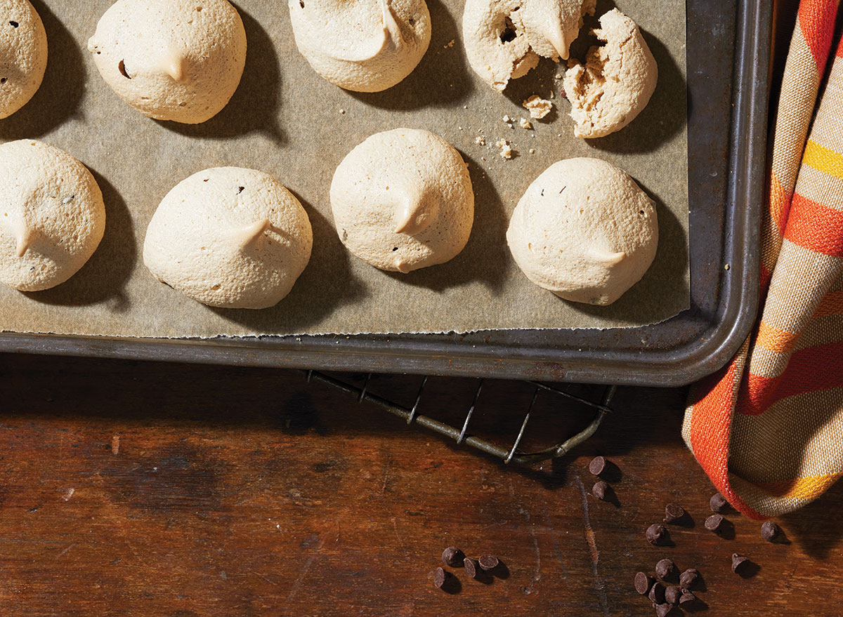 chocolate coffee meringues on a baking sheet with chocolate chips and tea towel