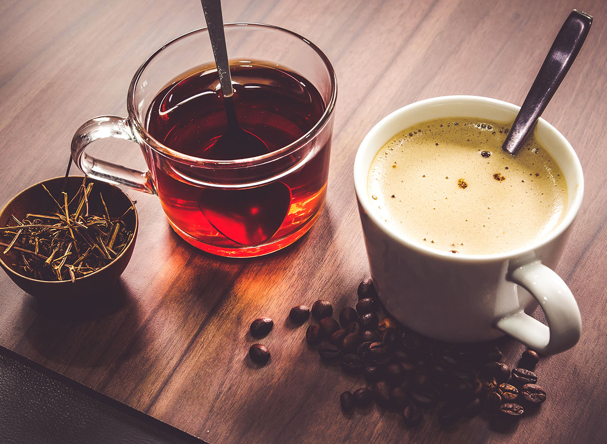 two mugs with coffee tea beans stems on wooden surface