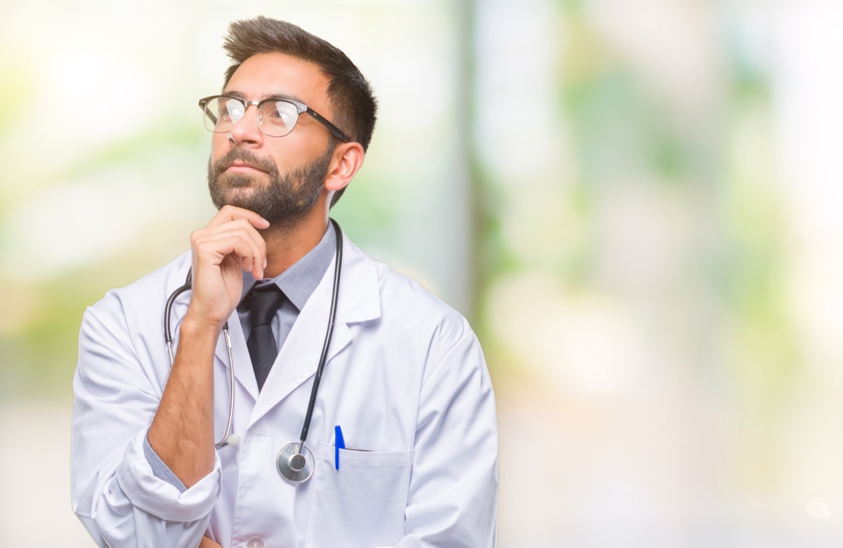 hispanic doctor man over isolated background with hand on chin thinking about question, pensive expression