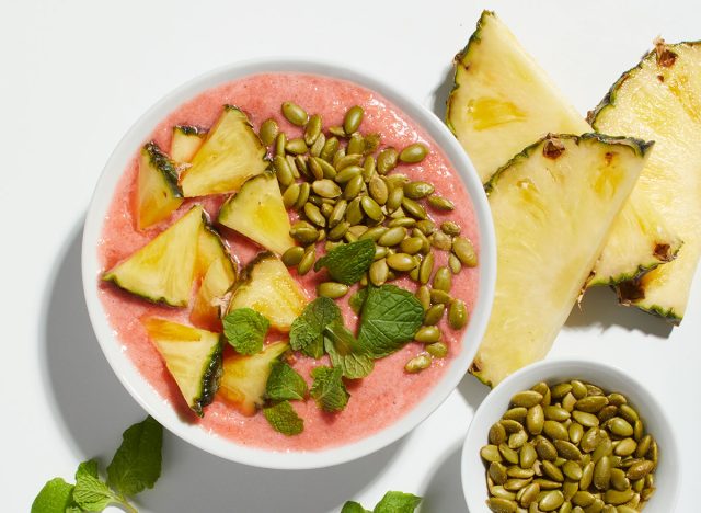 Dragon fruit smoothie bowl with pineapple pieces and pepitas
