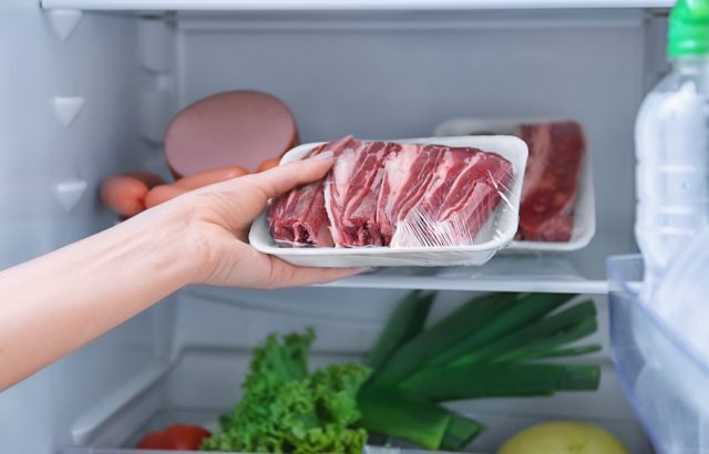 Woman putting raw meat in refrigerator