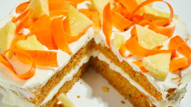 ginger carrot pineapple cake sliced with carrot and pineapple toppings on a white table
