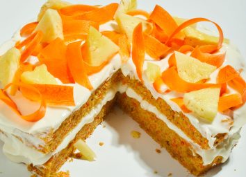 ginger carrot pineapple cake sliced with carrot and pineapple toppings on a white table