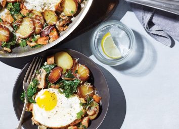 plate of italian hash with fried egg next to skillet and water glass