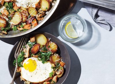 plate of italian hash with fried egg next to skillet and water glass