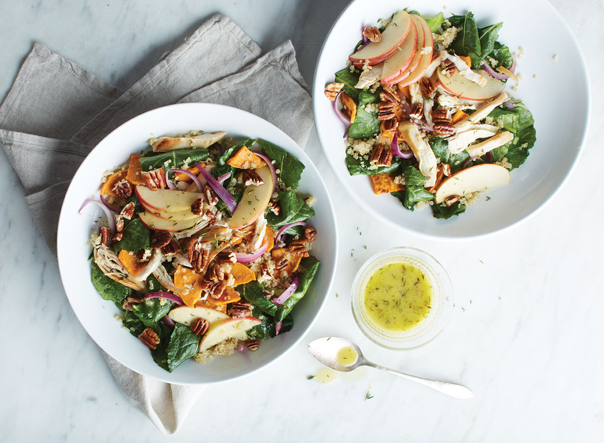 kale quinoa salad with apples and walnuts in two white bowls