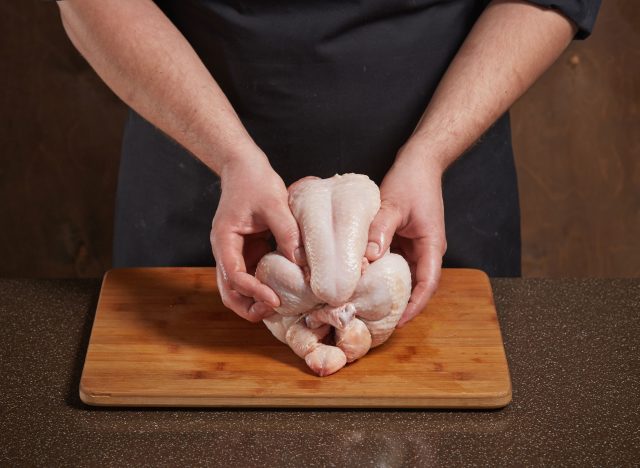 man prepping raw chicken