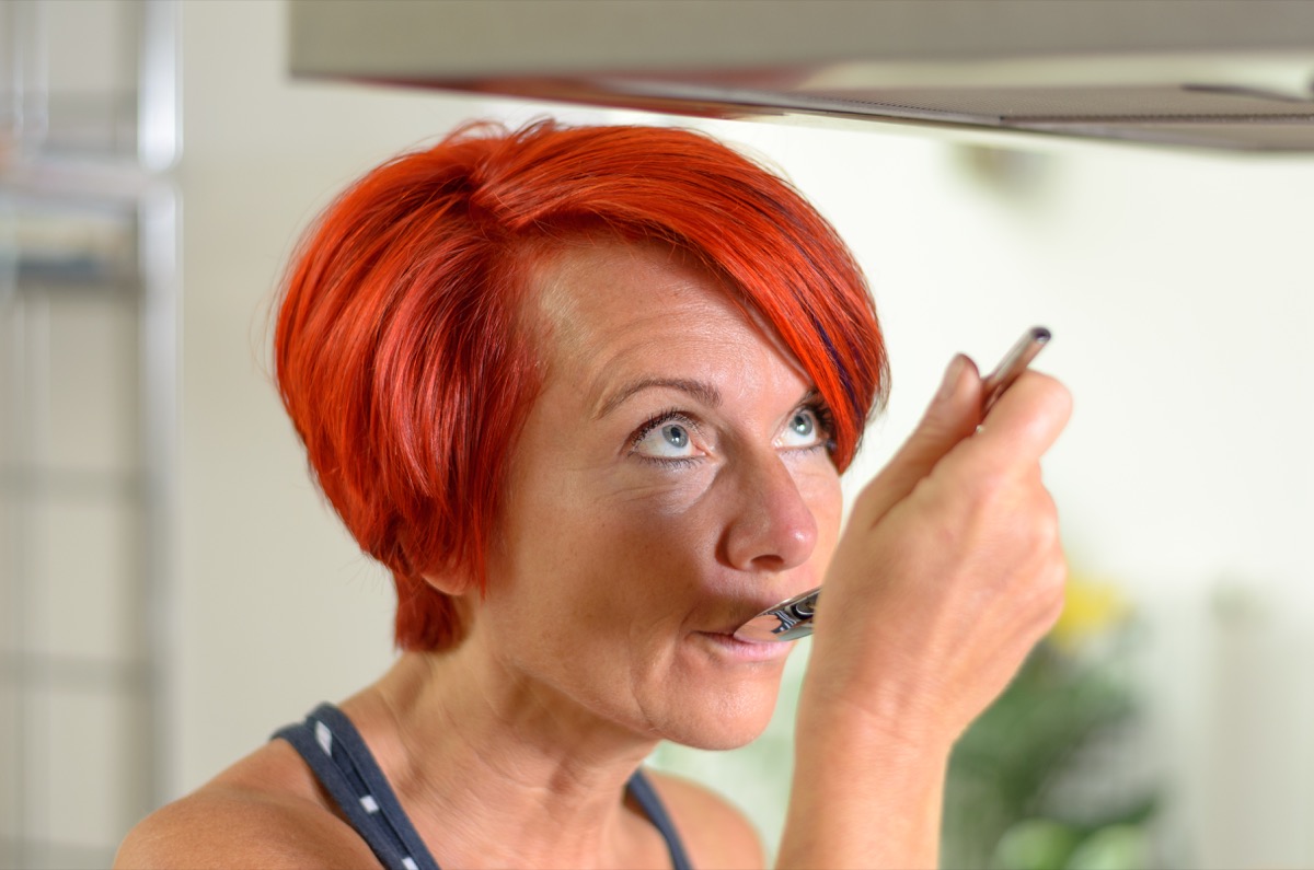 Close up Adult Redhead Woman in Sleeveless Shirt, Tasting her Recipe using a Spoon