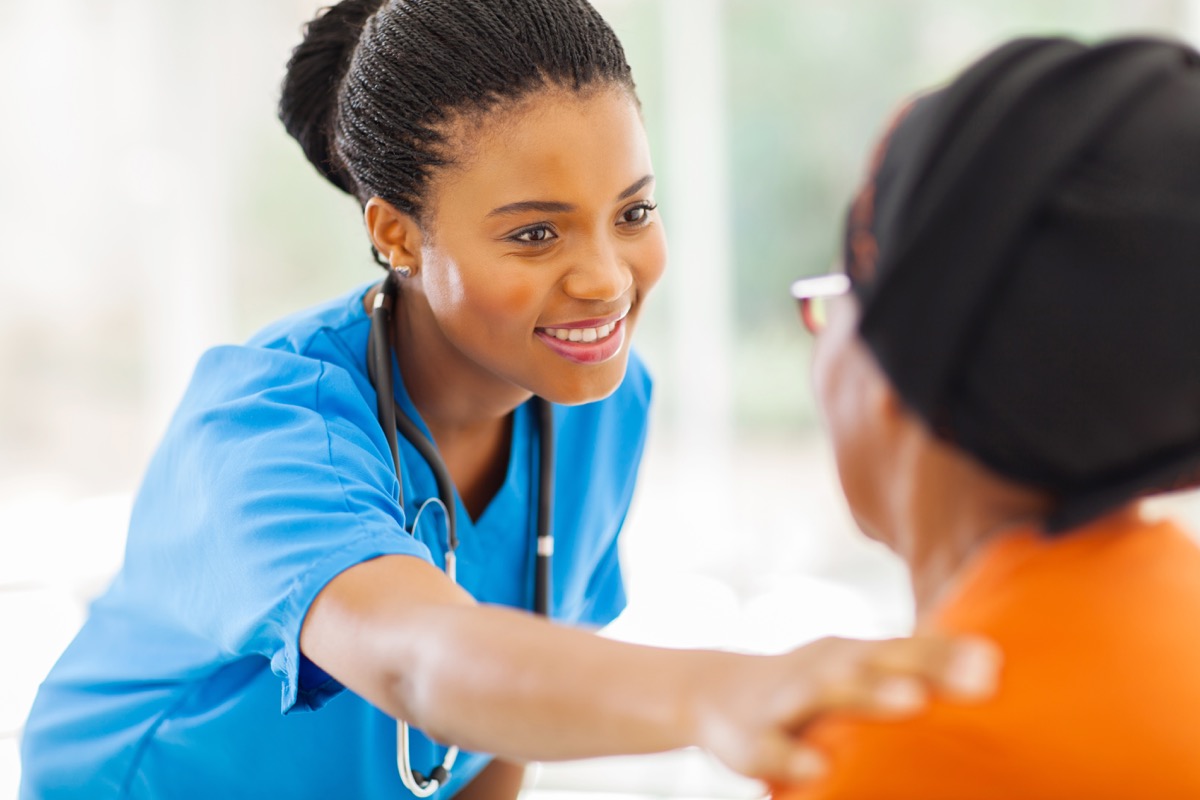 medical nurse comforting senior patient in office