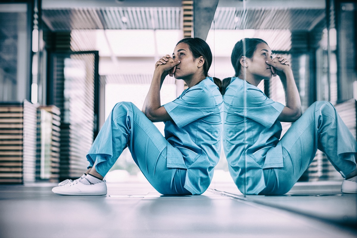 Worried nurse sitting in hospital corridor