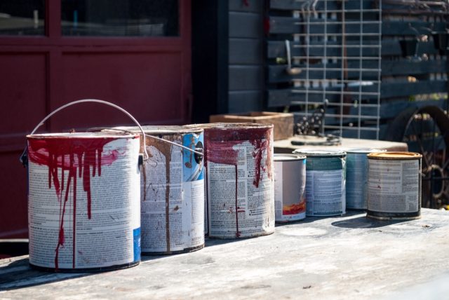 Old paint cans in front of a garage