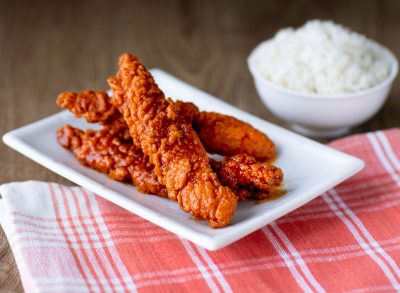 panda express sichuan hot chicken on red and white tablecloth with bowl of white rice