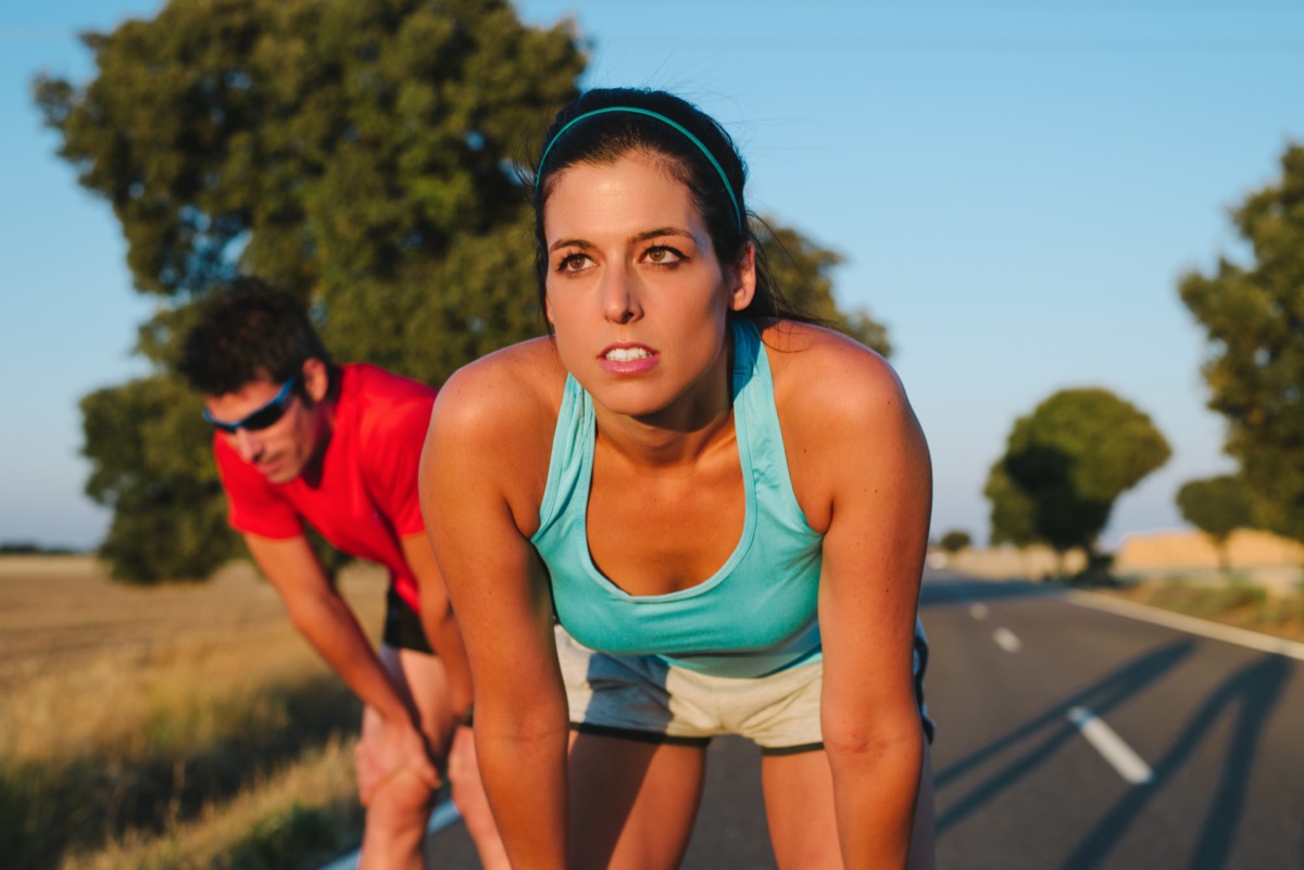 marathon. Tired female runner and man resting and breathing