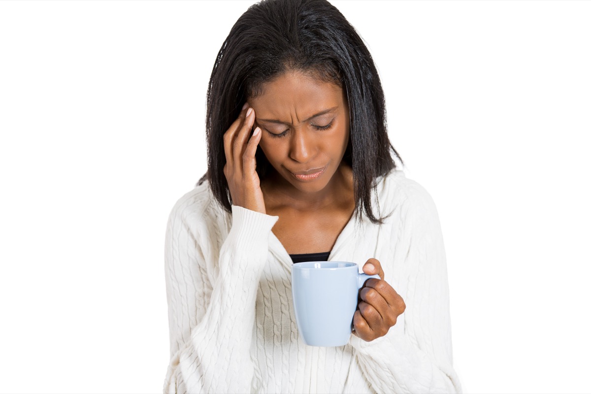 Tired stressed sad woman looking at cup of coffee isolated on white background