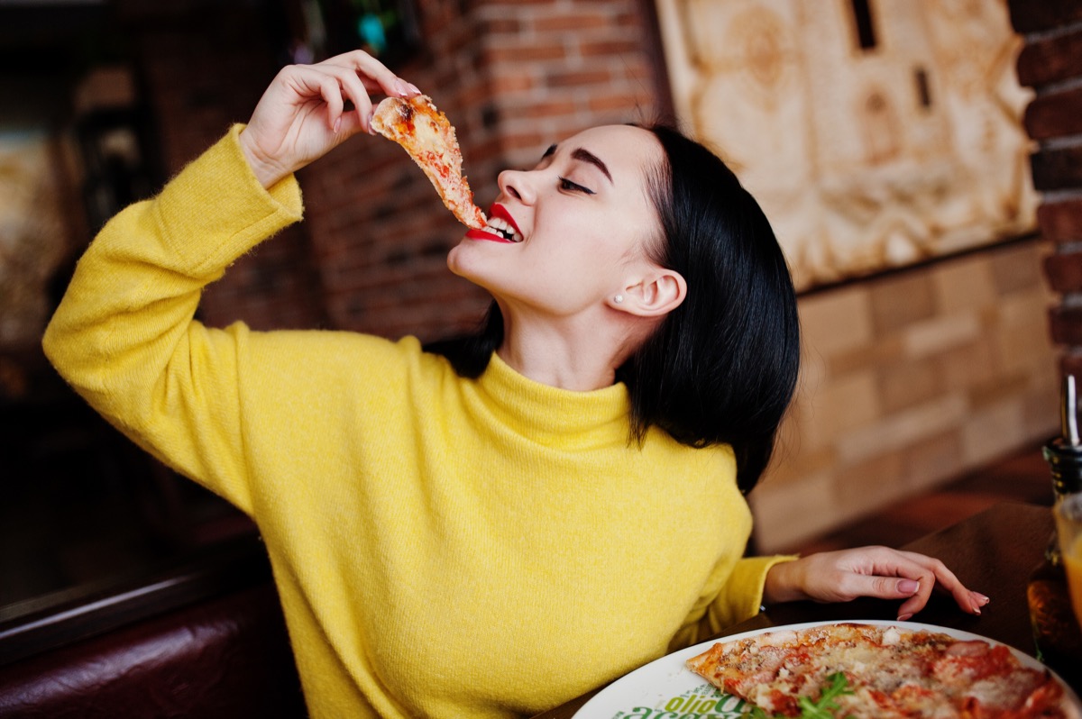 girl in yellow sweater eating pizza at restaurant