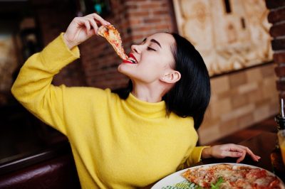 girl in yellow sweater eating pizza at restaurant