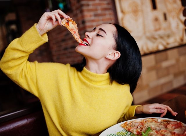 girl in yellow sweater eating pizza at restaurant