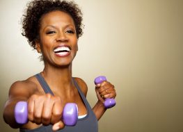 Happy fitness woman lifting dumbbells smiling and energetic