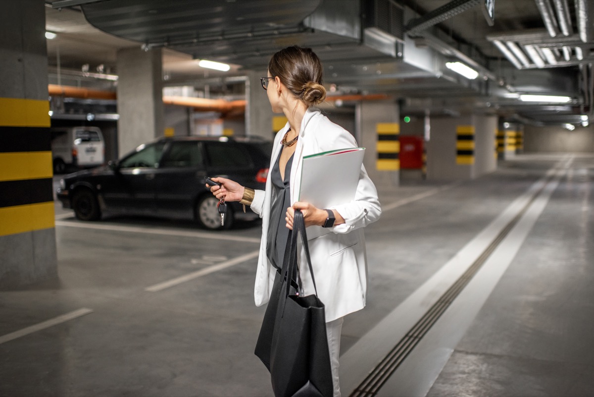 Young business woman walking with car keys in the underground parking of the new residential building - Image