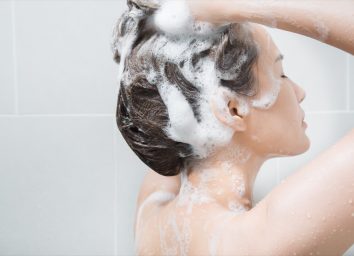 Woman in shower washing hair with shampoo