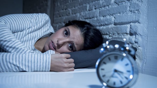 hispanic woman at home bedroom lying in bed late at night trying to sleep suffering insomnia sleeping disorder or scared on nightmares looking sad worried and stressed