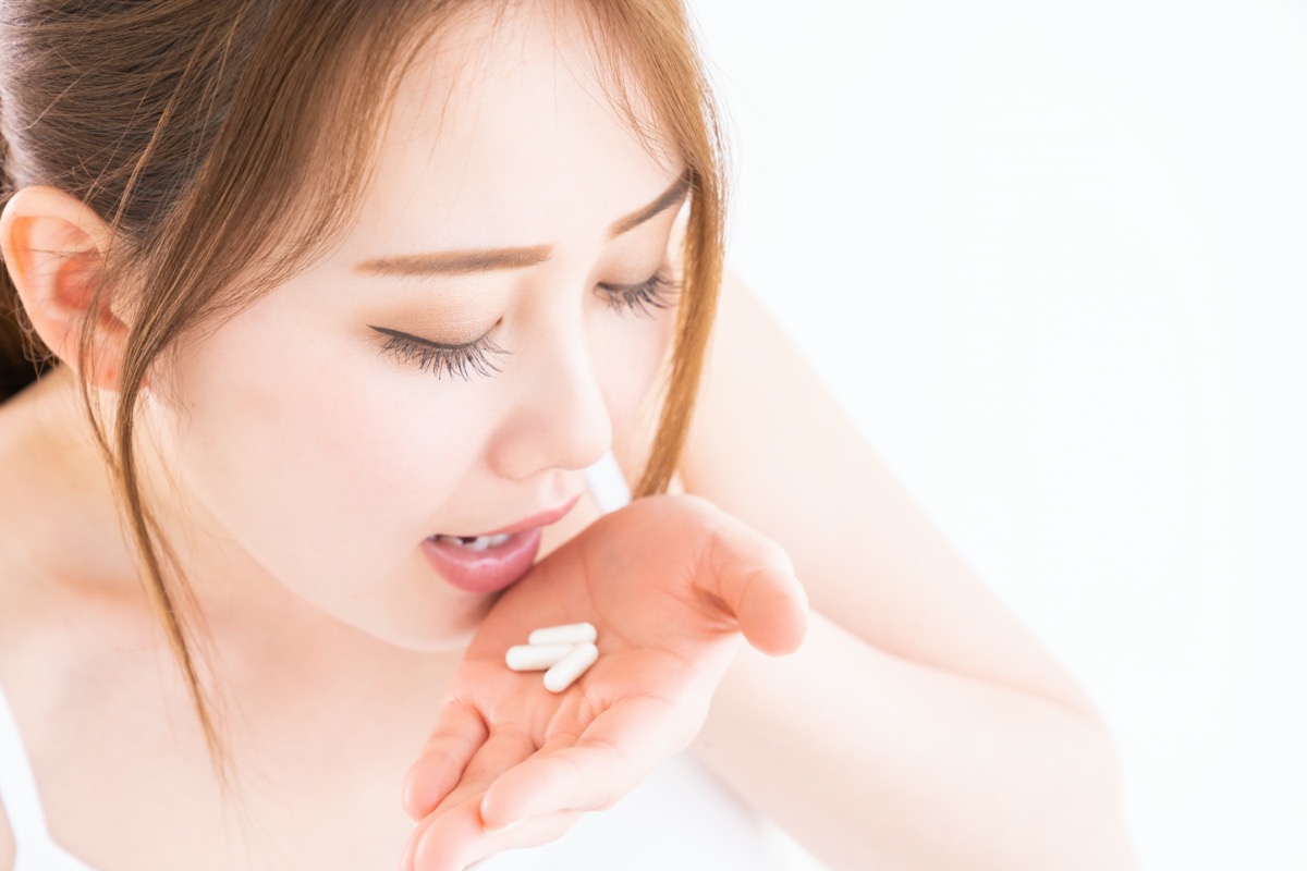 woman takes medicine capsules
