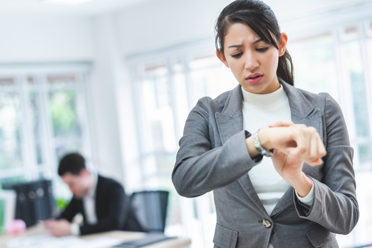 Asian business woman looking at the watch time worried and afraid of getting late to meeting