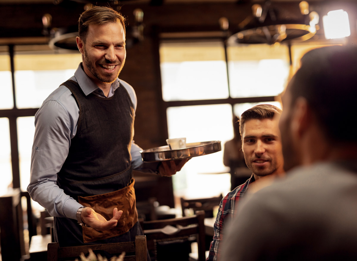 Waiter acting friendly to customers at a restaurant.