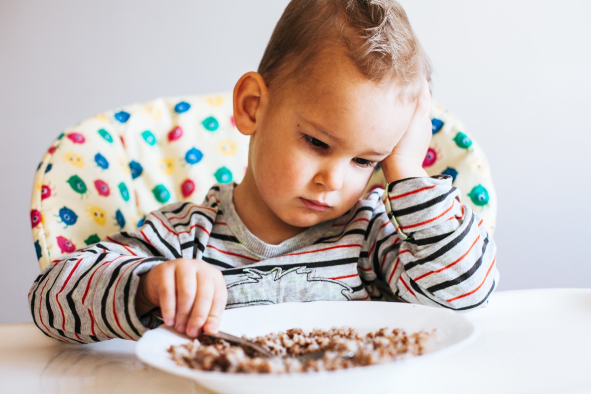 Portrait of child with no appetite in front of the meal