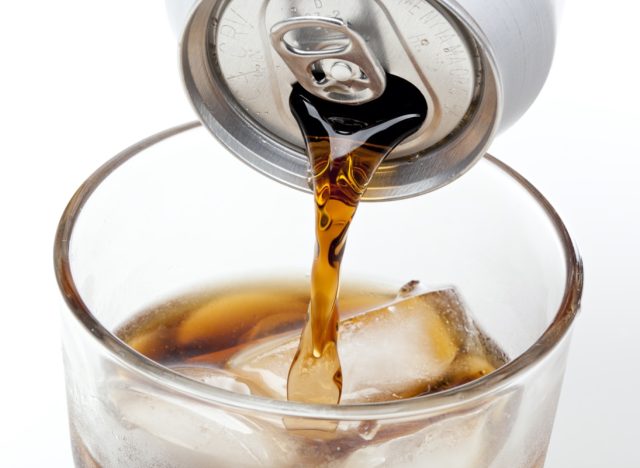 Brown soda in a clear glass against a white background