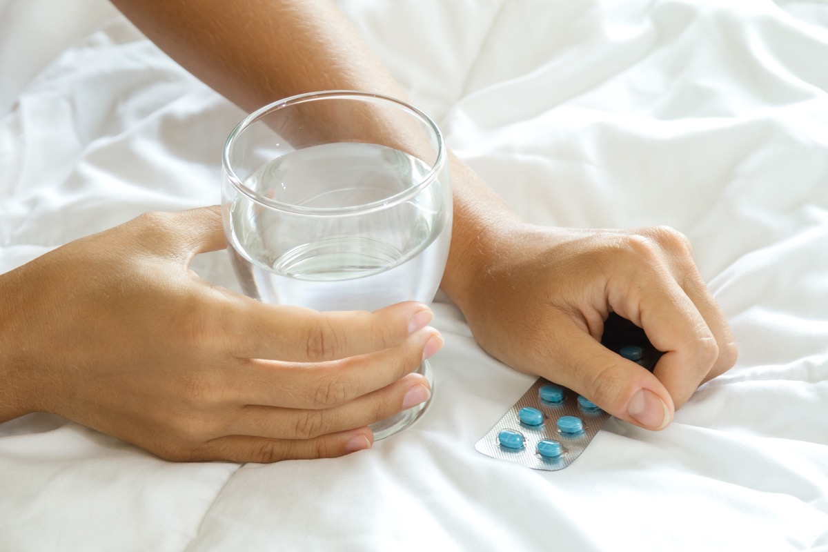 Female hands with a glass of water and blister pack with pills