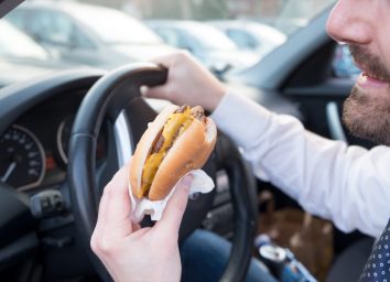 Man eating an hamburger while driving car