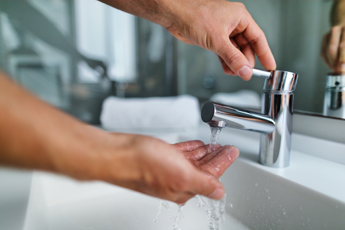 fingers under hot water out of a faucet of a sink