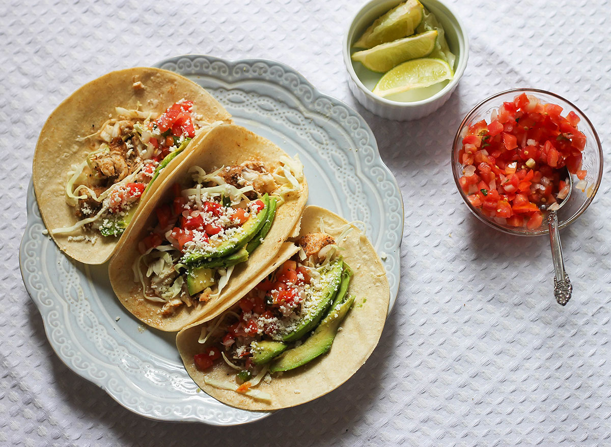 fish tacos on a plate with limes and pico de gallo