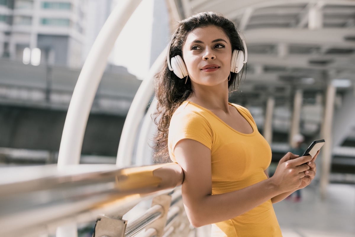 woman wearing bluetooth headphones listening to music in the city