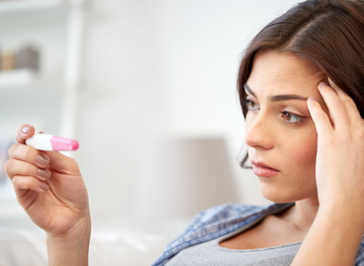 Woman with infertility taking a pregnancy test looking disappointed