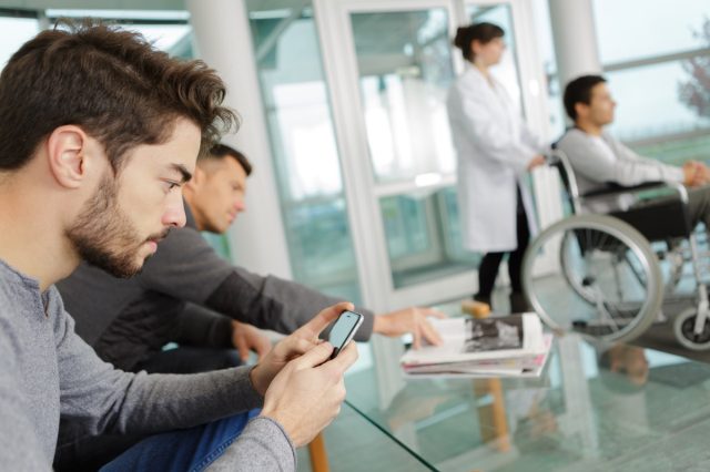 man use smart phone while waiting at a clinic