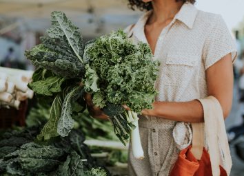 woman holding a bundle of two different types of kale