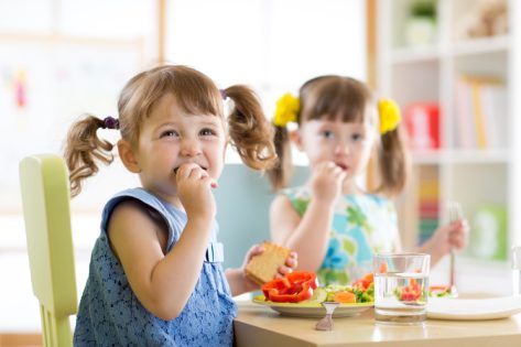 young girls with pigtails eating snack at a table, peanut free preschool snacks