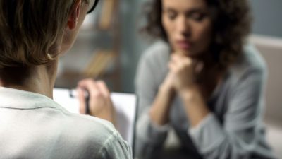 depressed woman talking to lady psychologist during session, mental health