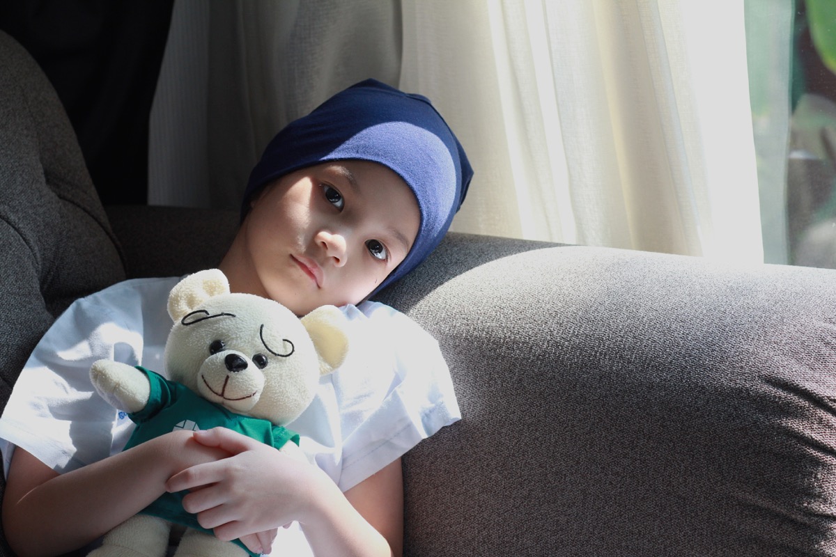 Patient kid lie down on couch or sofa in patient suit with her doll