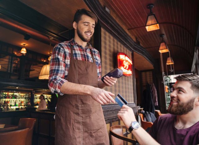 Waiter taking card as customer pays the bill.