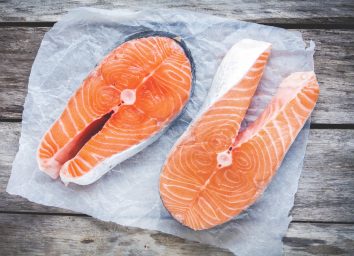 wild vs farmed salmon raw fillets on parchment paper