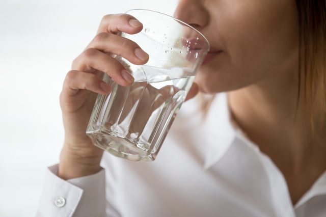 Dehydrated woman feeling thirsty holding glass drinking filtered pure mineral fresh water for body refreshment or energy recovery, dehydration problem, hydration