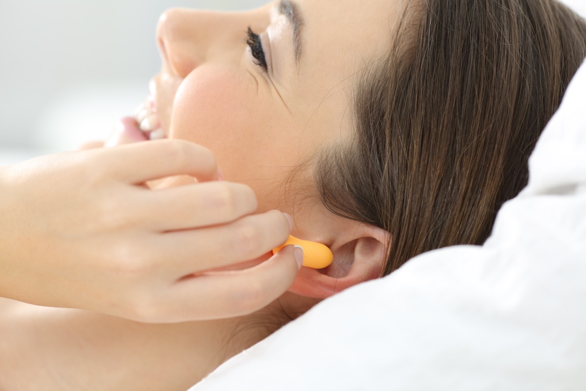 woman hand putting ear plugs to sleep on a bed at home