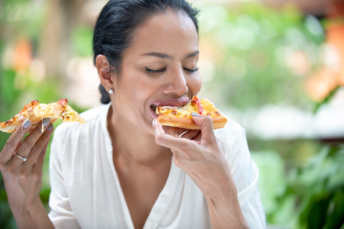 middle-aged woman are laughing holding and eating pizza