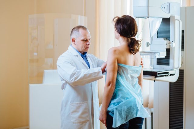 Doctor examining woman in hospital. Female patient listens to mammography technologist during survey. Explains importance of breast cancer prevention