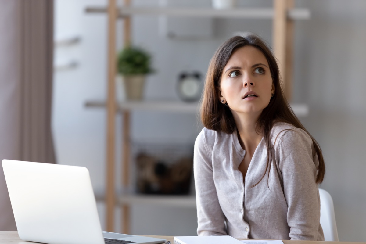 Confused young woman sit at office home desk working at laptop