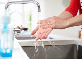 Woman Washing Hands In Kitchen Sink