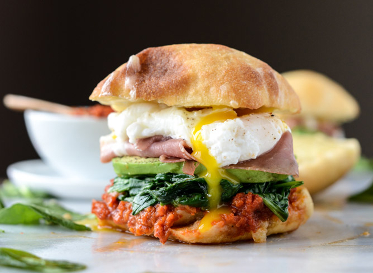 Breakfast sandwich with egg, ham, avocado on a ciabatta roll.